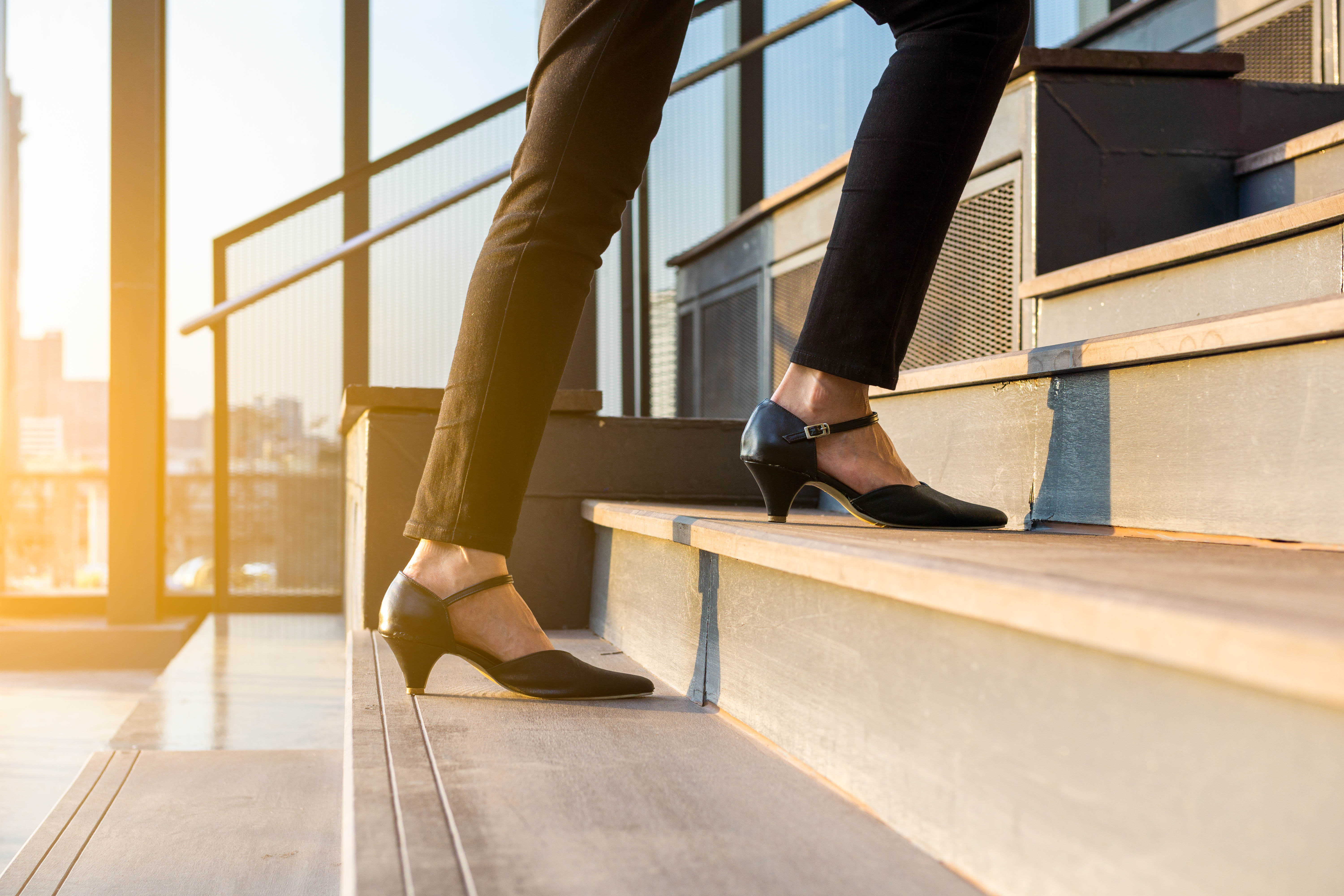 Woman walks upstairs outside, close-up on her short heels